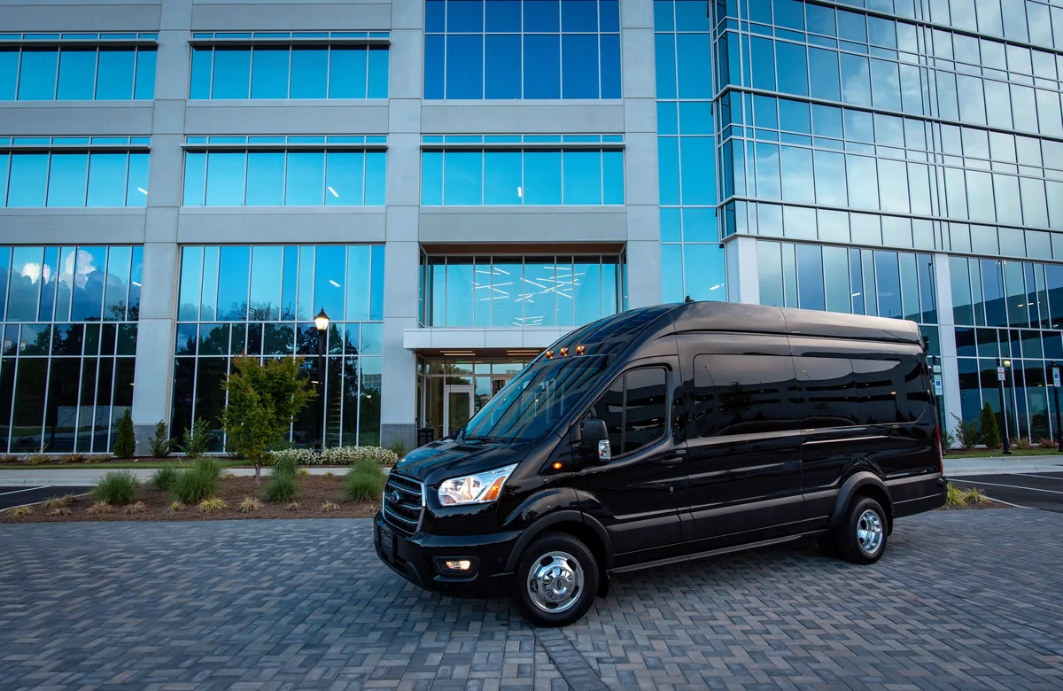 Crni premium kombi za grupne transfere ispred moderne poslovne zgrade